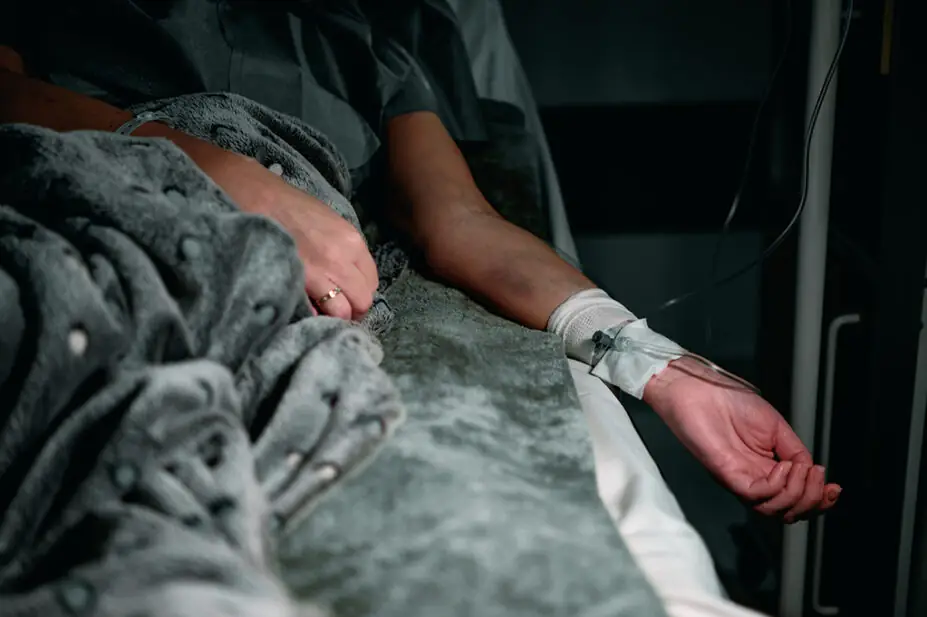 A patient lays in a sick bed, suggestive of terminal illness