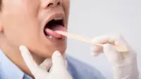 A healthcare professional checks the throat of a patient
