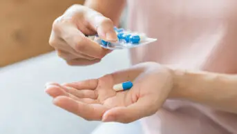A woman takes a antibiotic tablet