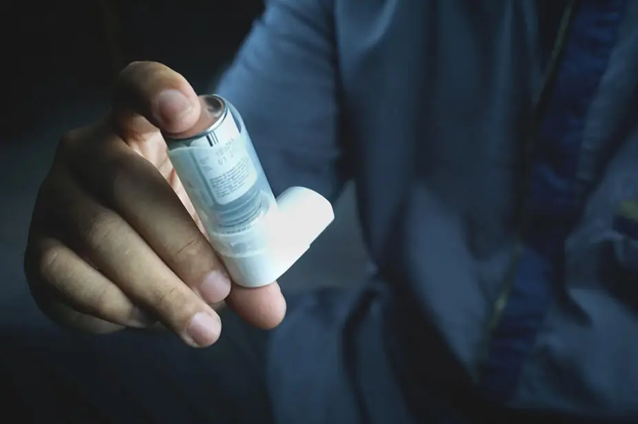 A man's hand holding an inhaler