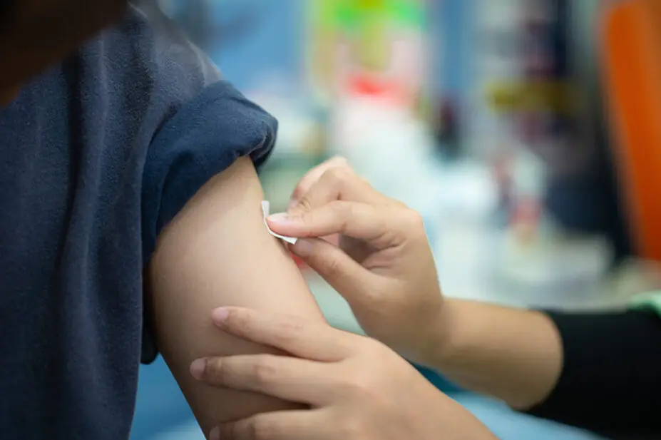 A healthcare professional applies a plaster after a flu vaccination
