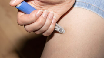 A woman injects herself with a weight-loss pen