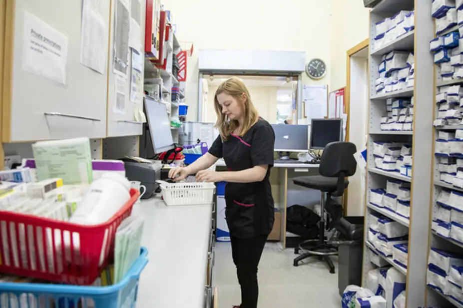 Trainee pharmacist in dispensary organising prescriptions