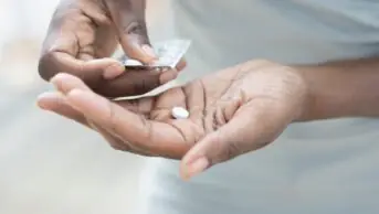 Woman taking pills from a blister pack.