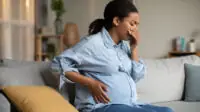 Pregnant woman leaning over with hand to her mouth looking nauseous