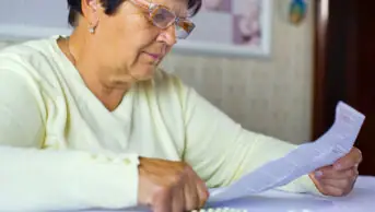 An older woman reads the medicines information for her prescription