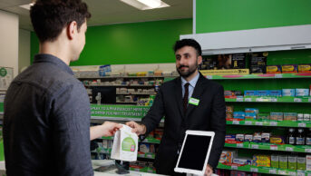 Pharmacist handing a male customer a prescription bag