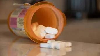 A spilled prescription bottle of oxycodone with tablets on a table