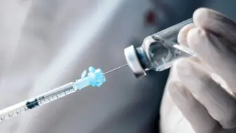A healthcare professional holds a syringe