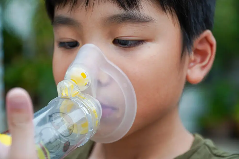 A child uses an inhaler with a spacer attached