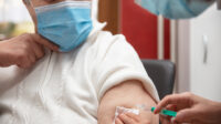 Older woman with grey hair is receiving a vaccination