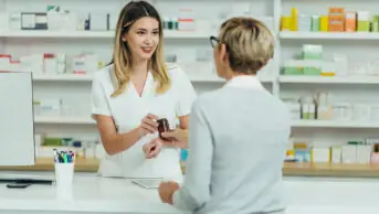 A pharmacist provides patient with medicine at the counter