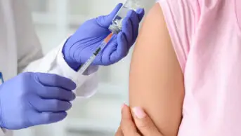 A healthcare professional prepares to administer a vaccine to a patient