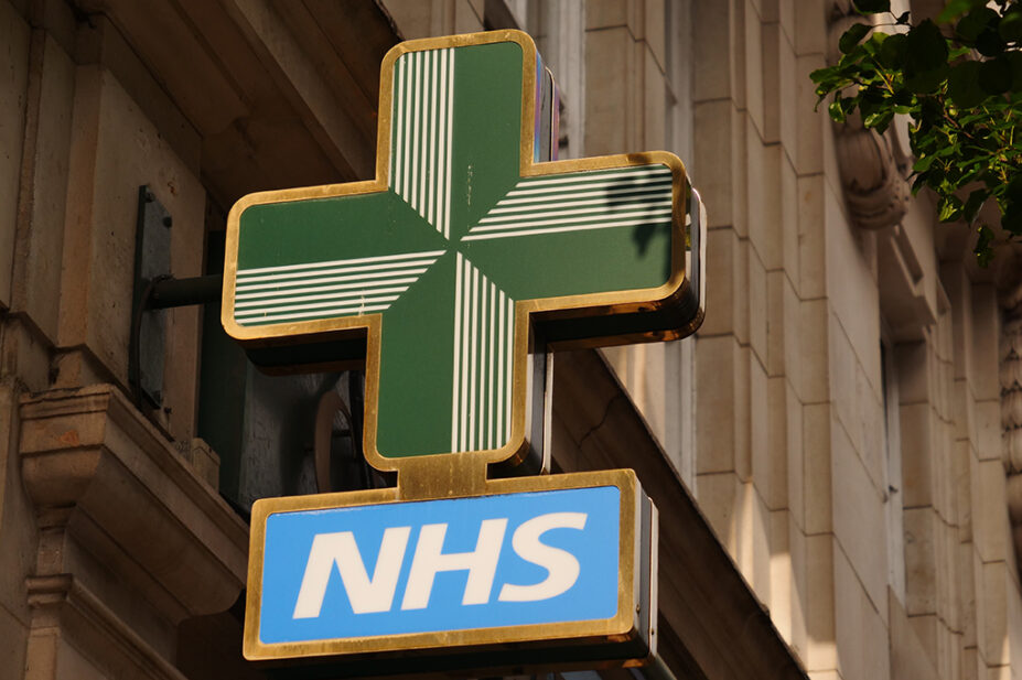 NHS pharmacy cross sign on exterior of building
