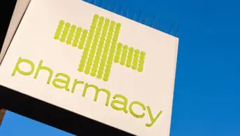 Green pharmacy cross sign outside a pharmacy store