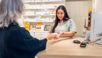 A pharmacist hands over-the-counter medicine to a patient