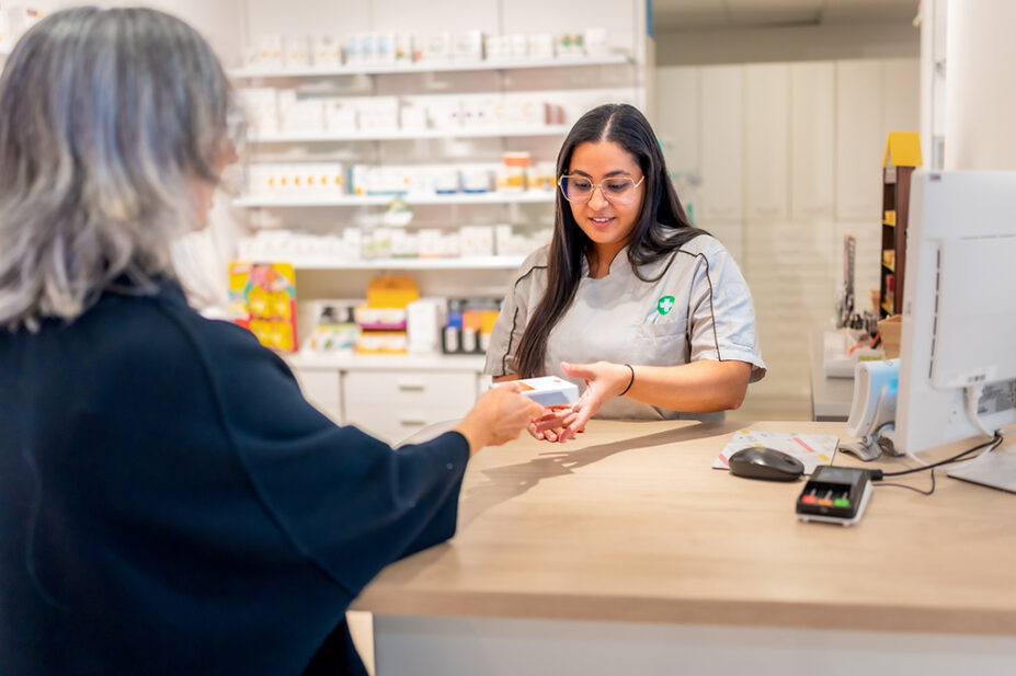 A pharmacist hands over-the-counter medicine to a patient