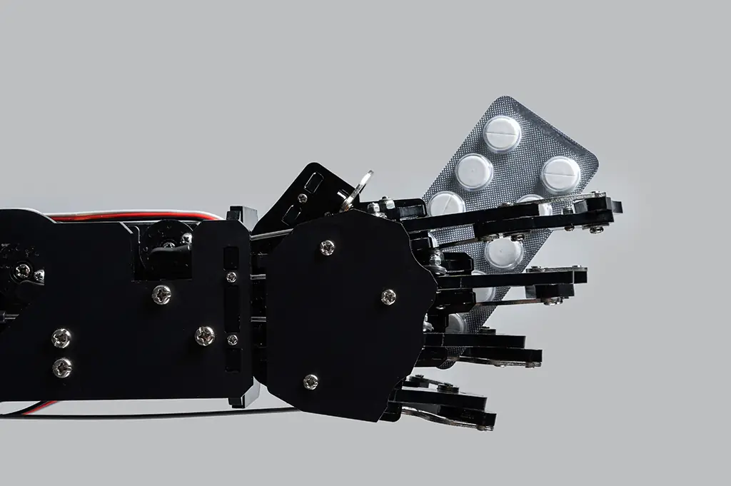 A robotic arm holding a blister pack of tablets