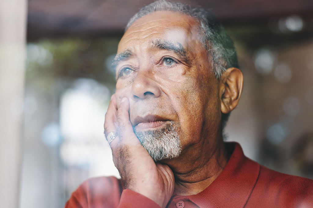 An older man looks out a window
