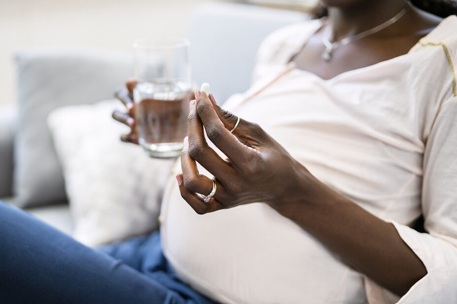 A pregnant woman takes medication with a glass of water