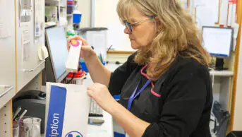 A pharmacist places a prescription in a bag