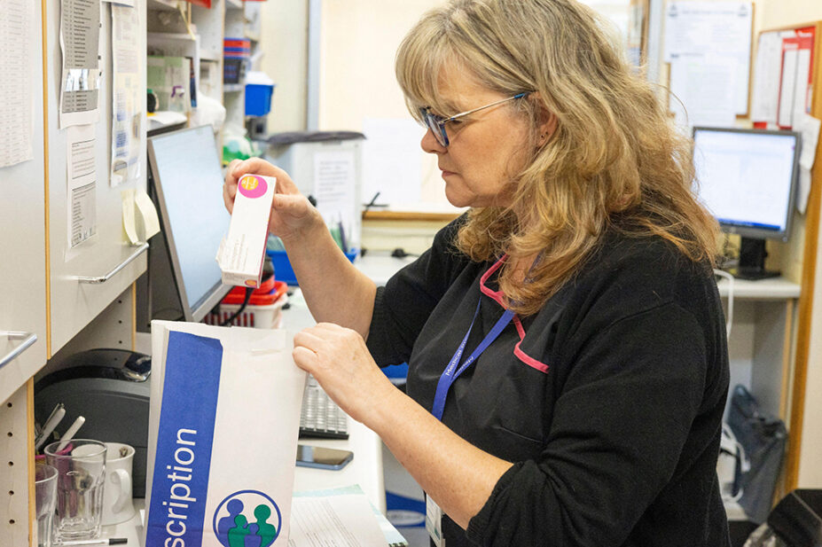 A pharmacist places a prescription in a bag