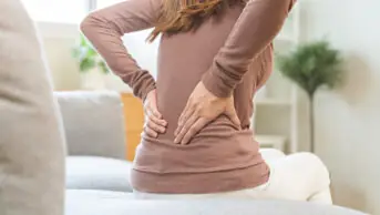A woman with chronic pain holds her back