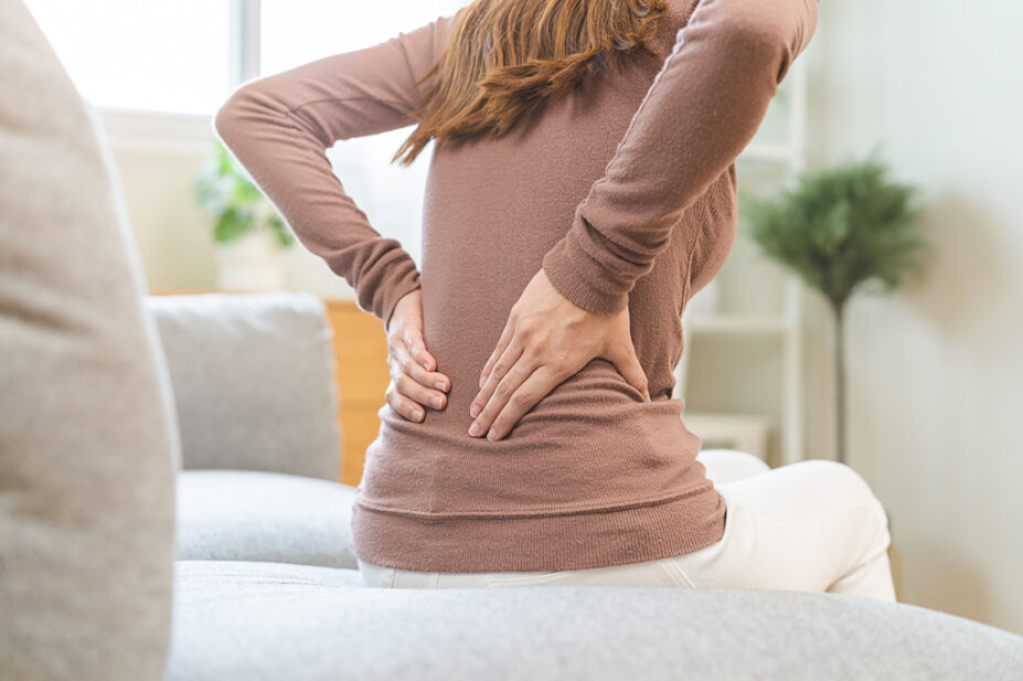 A woman with chronic pain holds her back