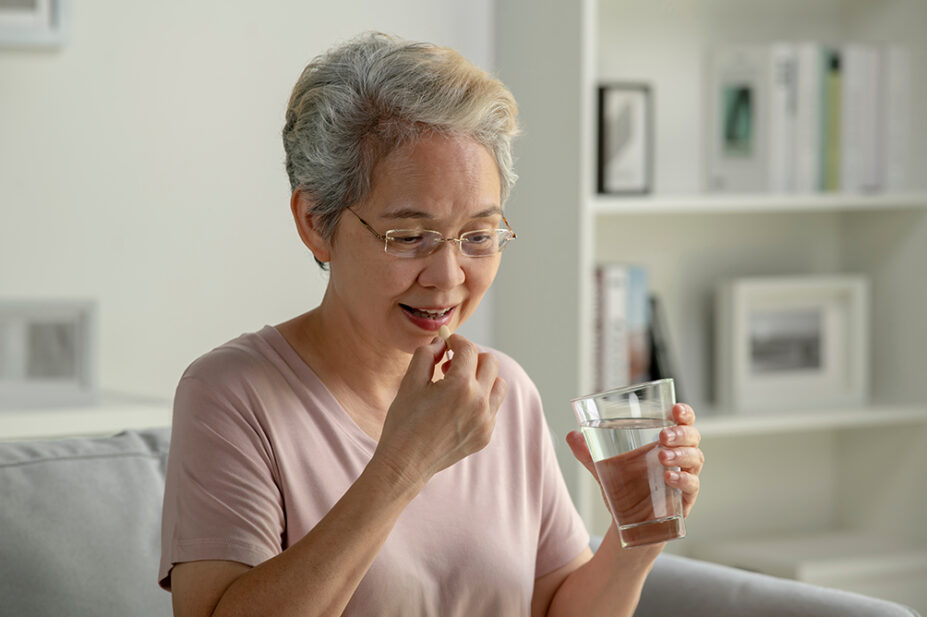 An older woman takes medication with a glass of water