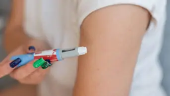 A woman holds a weight-loss injection