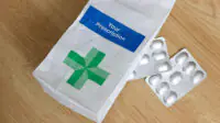 An NHS prescription bag with two packets of medicines