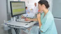 A healthcare professional checks a patient's details on a computer in hospital