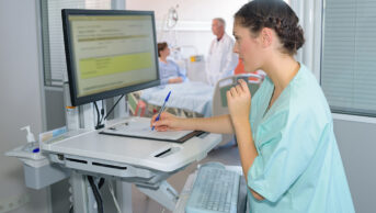 A healthcare professional checks a patient's details on a computer in hospital