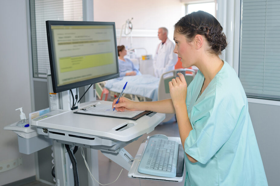 A healthcare professional checks a patient's details on a computer in hospital