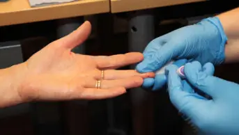 A healthcare professional pricks a patient's finger