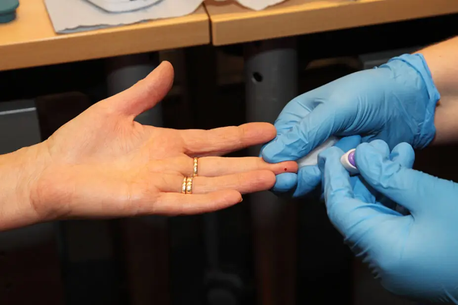A healthcare professional pricks a patient's finger