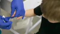 A clinician drawing blood from a child's finger for analysis