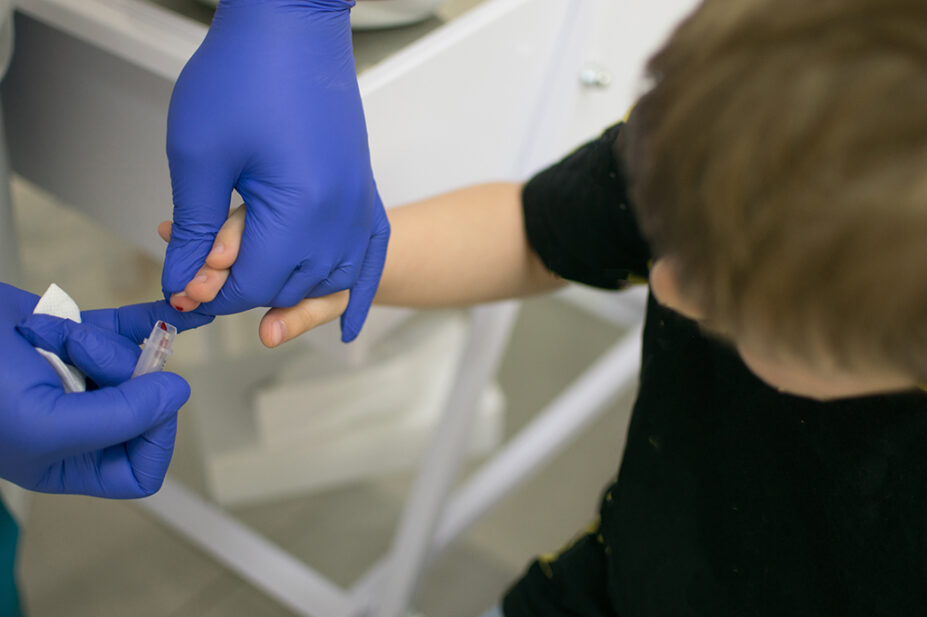 A clinician drawing blood from a child's finger for analysis