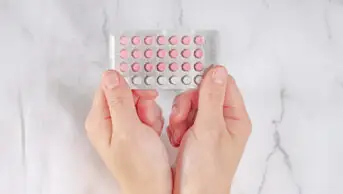 A person's hands holding oral contraceptives