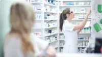 A pharmacist reaches for medication on a shelf