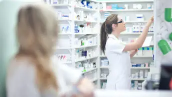 A pharmacist reaches for medication on a shelf