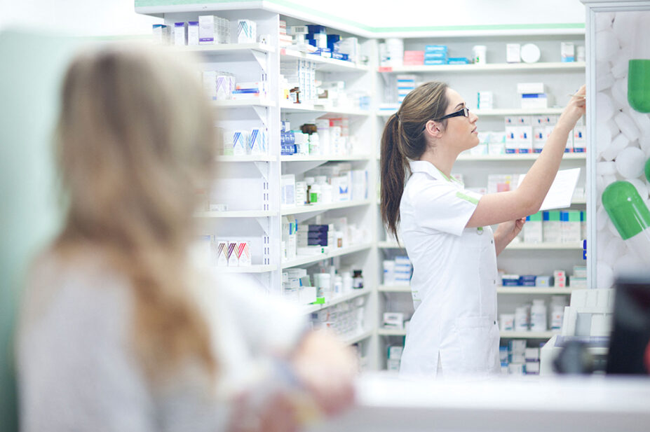 A pharmacist reaches for medication on a shelf