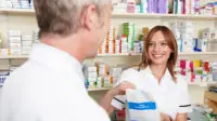 A pharmacist hands a patient his prescription