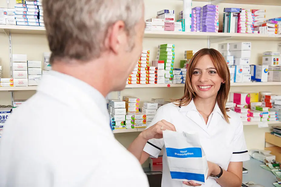 A pharmacist hands a patient his prescription