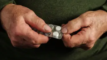 Older male holding a blister packet of tablets