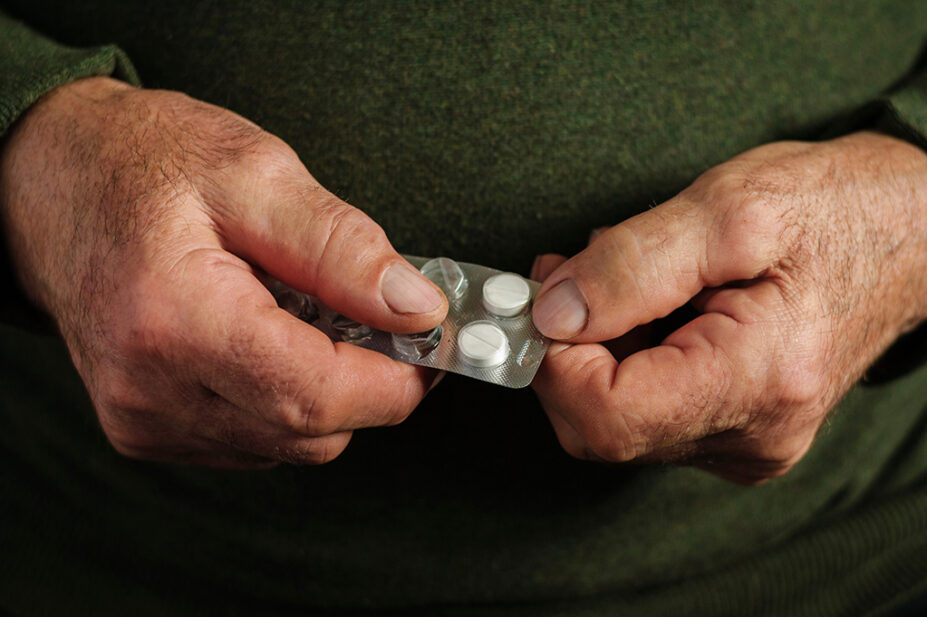 Older male holding a blister packet of tablets