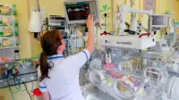 A healthcare professional works in a neonatal intensive care unit