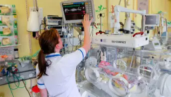 A healthcare professional works in a neonatal intensive care unit