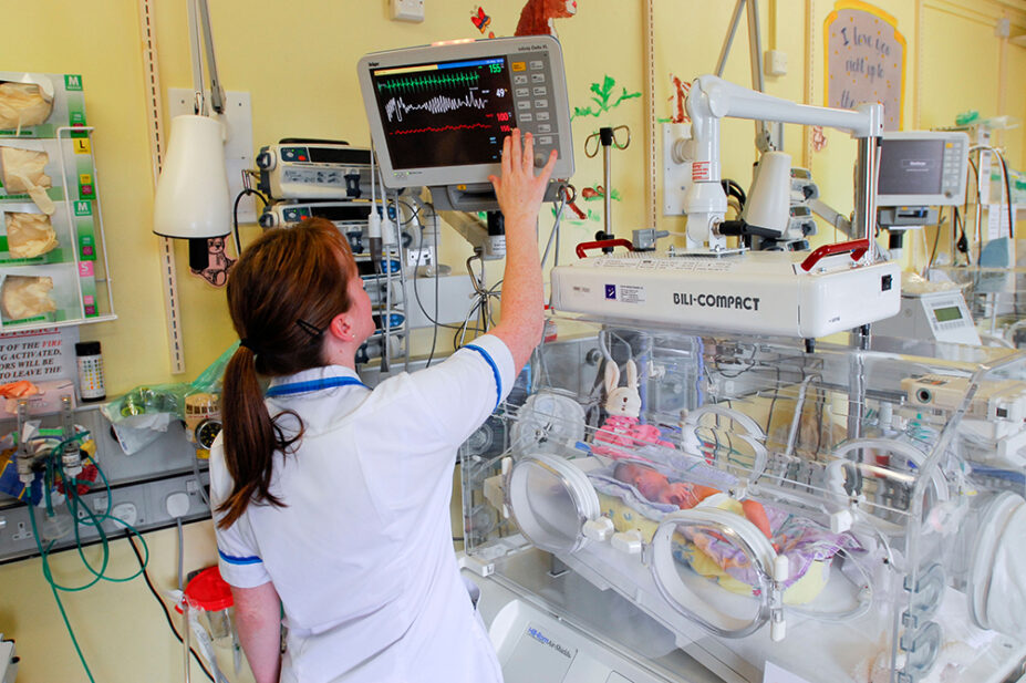 A healthcare professional works in a neonatal intensive care unit