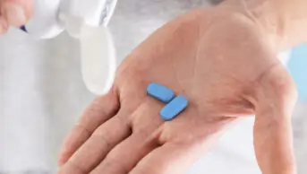 Man holding PrEP tablets in palm of hand